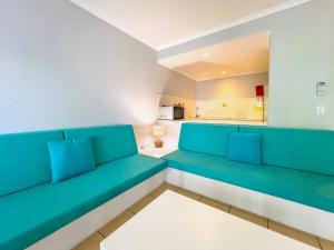 a living room with blue couch and a kitchen at Mango Reef House - Airlie Beach in Airlie Beach +44 photos