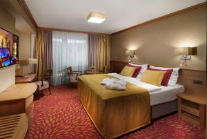 a hotel room with a large bed with yellow and red pillows at Harmony Club Hotel in Špindlerův Mlýn