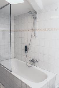 La salle de bains carrelée de blanc est pourvue d'une douche et d'une baignoire. dans l'établissement Le Virage bistro en hotel, à Maastricht
