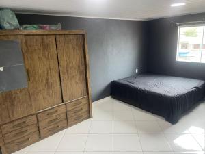a bedroom with a bed and a large wooden cabinet at Lareaconchego in São Pedro da Aldeia