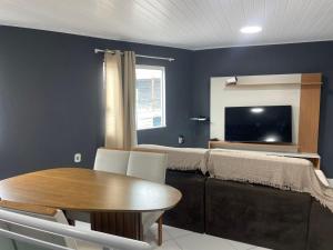 a room with a table and a bed and a tv at Lareaconchego in São Pedro da Aldeia