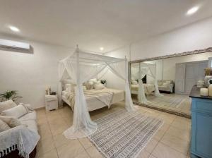 a bedroom with a canopy bed and a mirror at White Orchid Villa Seminyak in Seminyak