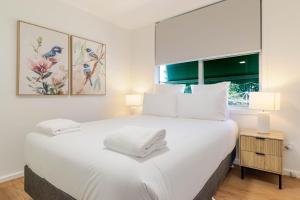 a bedroom with a large white bed with a window at Botanic Base - Designed for Ease & Comfort in Wagga Wagga