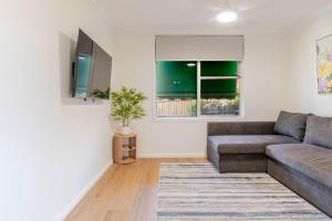 a living room with a couch and a tv at Botanic Base - Designed for Ease & Comfort in Wagga Wagga