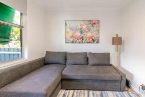 a couch in a living room with a painting on the wall at Botanic Base - Designed for Ease & Comfort in Wagga Wagga +15 photos