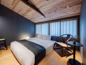 a bedroom with a large white bed and a chair at Itose Machiya House in Kanazawa