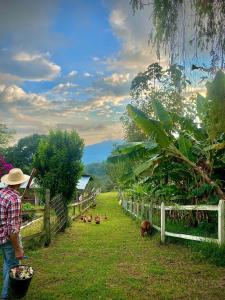 a man standing next to a fence with animals in a field at Finca Agrópolis de Silvania in Silvania