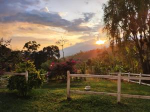 a fence in a field with the sunset in the background at Finca Agrópolis de Silvania in Silvania