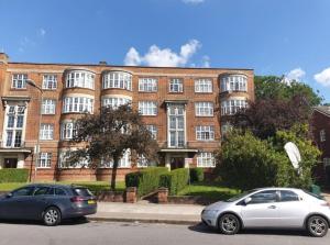 two cars parked in front of a brick building at Spacious Modern 3 Bed Apartment in Hendon NW4 in Colindale