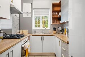 a kitchen with white cabinets and a sink at Spacious Modern 3 Bed Apartment in Hendon NW4 in Colindale
