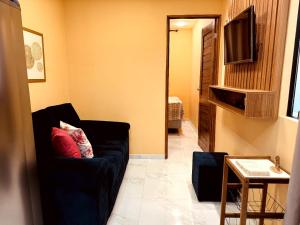 a living room with a black couch and a television at CASA CONTAINER Vsa in Vitória de Santo Antão