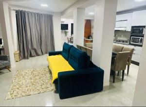 a living room with a blue couch and a kitchen at Casa de Hóspedes Kipper in São Gabriel