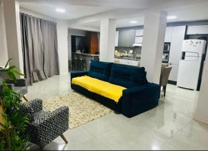 a living room with a blue couch and a kitchen at Casa de Hóspedes Kipper in São Gabriel