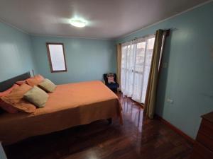a bedroom with a bed with orange sheets and a window at Casa Flor del aire in La Serena