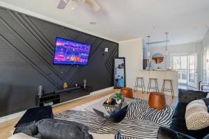 a living room with a couch and a tv on a wall at Fireside Double Kings Midtown Luxe Suite in Houston