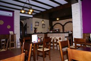 uma sala de jantar com mesas e cadeiras e um bar em Hotel El Romeral em Almadén de la Plata