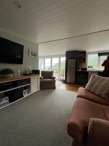 a living room with a couch and a tv at Portobello Bach Double Cove in Lochmara Bay