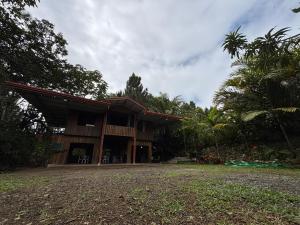 een gebouw met een veranda en een palmboom bij Mountain Retreat Refugio de Aves in Turrialba