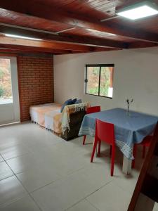 a bedroom with a bed and a table and chairs at Chale Primavera in Benedito Novo +11 photos