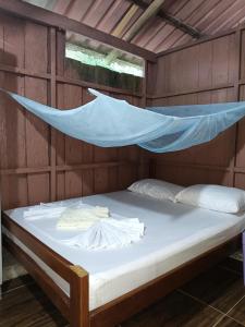 ein Bett in einem Holzzimmer mit Moskitonetz in der Unterkunft Hospedaje Rural Shihumar in Coquí