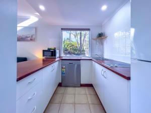 a kitchen with white cabinets and a sink and a microwave at Whispering Palms at Mango House in Airlie Beach +46 photos