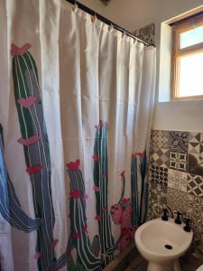 a bathroom with a shower curtain with cactus at Vivir en Maimará in Maimará +10 photos