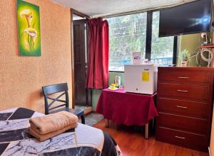 a bedroom with a bed and a dresser with a tv at Hostal La Estación Quito in Quito