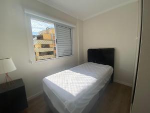 een witte slaapkamer met een bed en een raam bij Apartamento no Centro em Poços de Caldas in Poços de Caldas