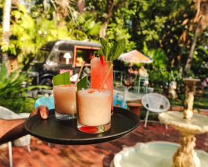 a person holding two cocktails on a tray at Suites by The Wellborn in Orlando