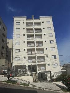 een groot wit gebouw met een hek ervoor bij Apartamento no Centro em Poços de Caldas in Poços de Caldas