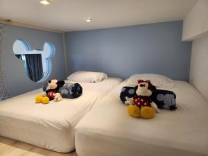 two beds with stuffed animals sitting on top of them at Sunway Grid Mickey House 4-5pax, 8mins to Legoland in Iskandar Puteri