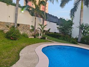 a swimming pool in a yard with palm trees at Departamento con ubicacion priviligiada cerca de la playa in Acapulco
