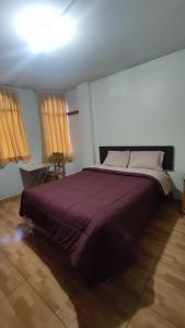 a bedroom with a large bed with a purple blanket at Huachuma Rooms in Huaraz
