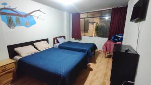 a bedroom with two beds and a television and a window at Huachuma Rooms in Huaraz