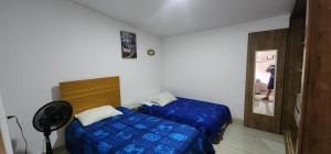 a bedroom with a blue bed and a fan at Casa de Playa Salgar in Puerto Colombia