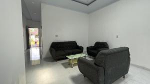 a living room with two couches and a table at Denggan KNO Guest House in Tanjungmorawa