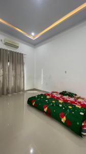 a green blanket on the floor of a room at Denggan KNO Guest House in Tanjungmorawa