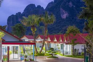 a row of buildings with palm trees in front of a mountain at Ruby Mountain View Resort Vang-vieng in Vang Vieng