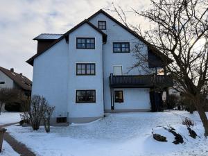 a large white house with snow on the ground at Komfortable moderne Ferienwohnung 43 qm in Köditz