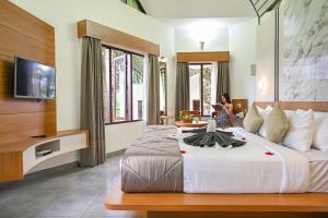 a woman in a hotel room with a large bed at Misty Lake Resorts Munnar By Sylora Hotels in Munnar