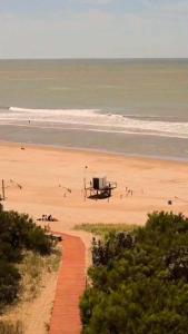 a beach with a boat on the sand and the ocean at Villa Gesell departamento frente al mar in Villa Gesell