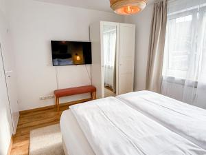 a white bedroom with a bed and a chair at City Apartments Gerlingen in Gerlingen