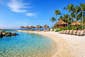 a beach with chairs and umbrellas and the ocean at 7BR Private Jacuzzi & Pool Villa Sleeps 16 Walk to Beach Lagoon and Golf in Puerto Aventuras