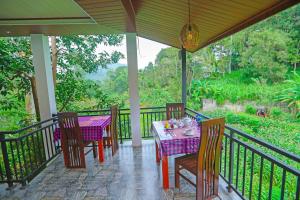 a porch with a table and chairs on a balcony at Forest Edge Villa in Ella