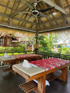 two picnic tables on a patio with a roof at Green Papaya Beach Resort, Koh Phangan in Salad Beach