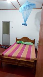 a bed with a colorful striped comforter in a room at Sinharaja Backpacker Homestay in Kandilpana