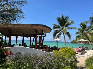 a beach with people sitting under umbrellas and the ocean at Green Papaya Beach Resort, Koh Phangan in Salad Beach