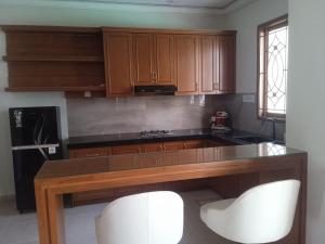 a kitchen with a counter and two white chairs at Villa Atlas in Batu