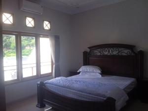 a bedroom with a bed and two windows at Villa Atlas in Batu