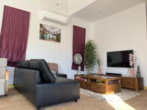 a living room with a black leather couch and a flat screen tv at Villa de Veluwe @ Hua Hin in Hua Hin